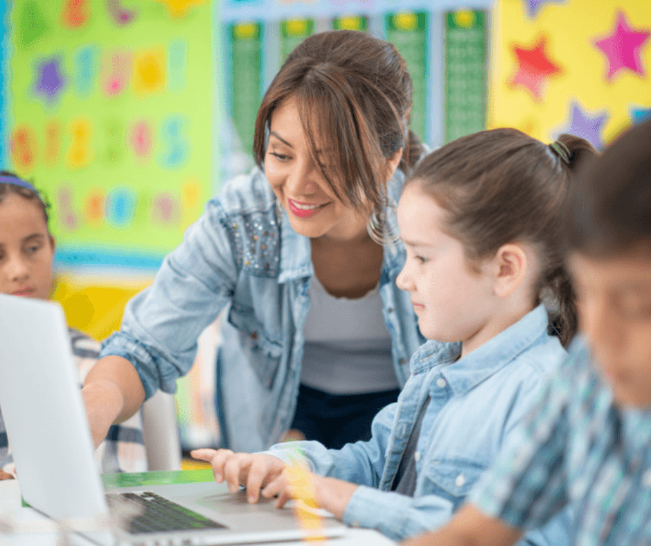 Teacher over childs shoulder pointing to computer scree