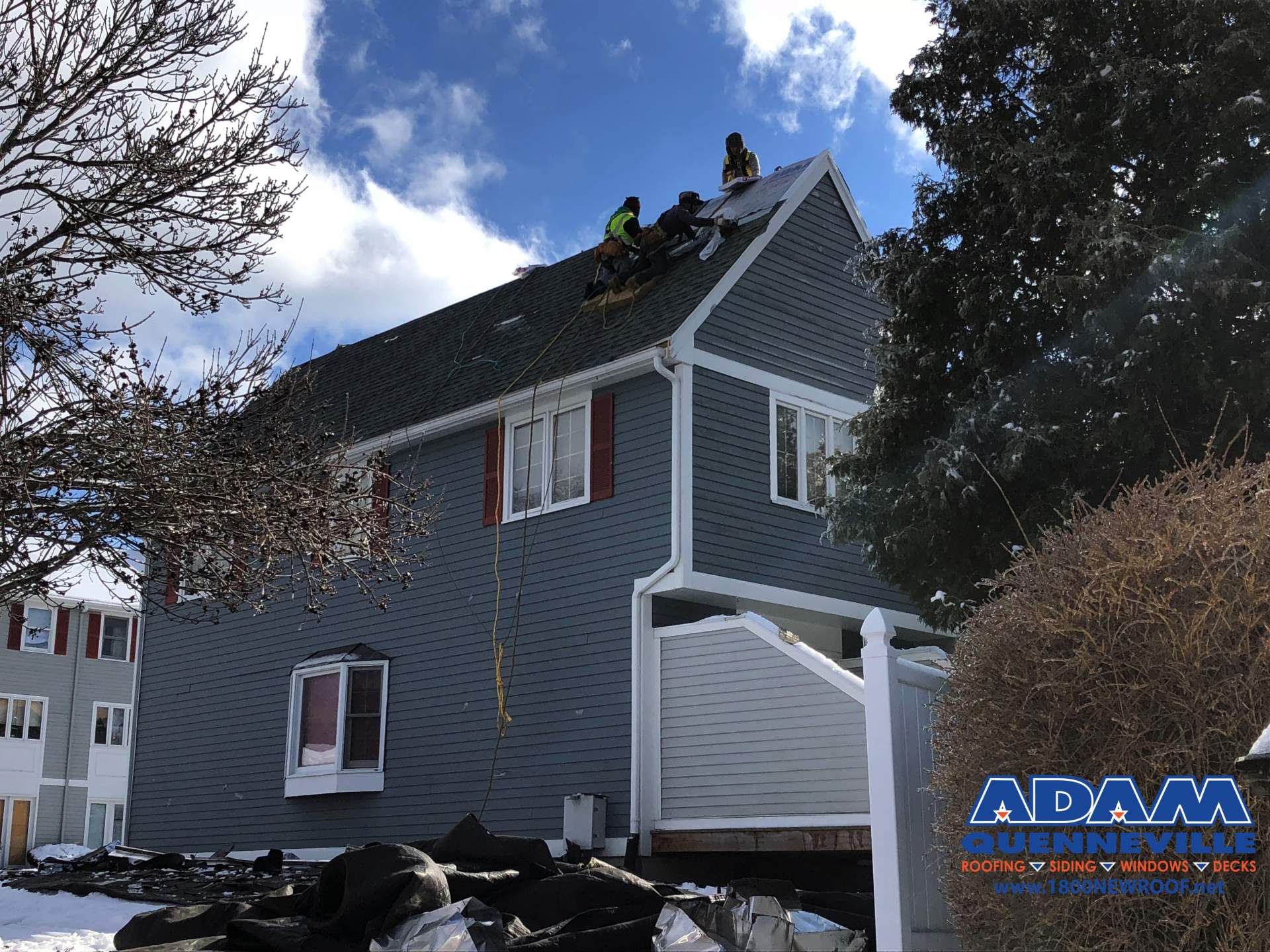 This is a photo of a local roofing and siding replacement project in progress with 3 works on the roof.