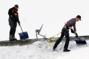 Roofers removing snow and ice from a roof