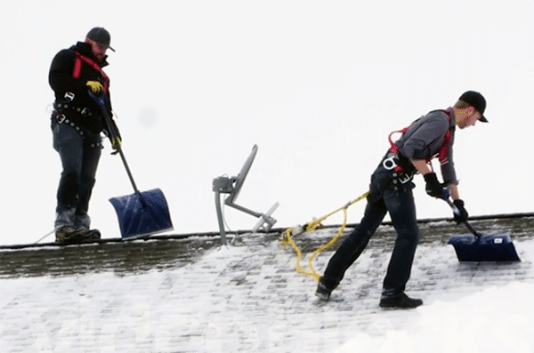 Roofers Removing Snow And Ice From A Roof
