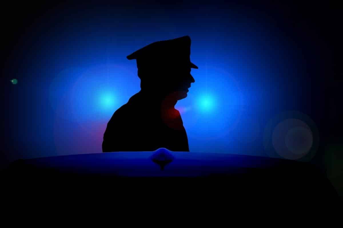 a policeman silhouetted by blue lights