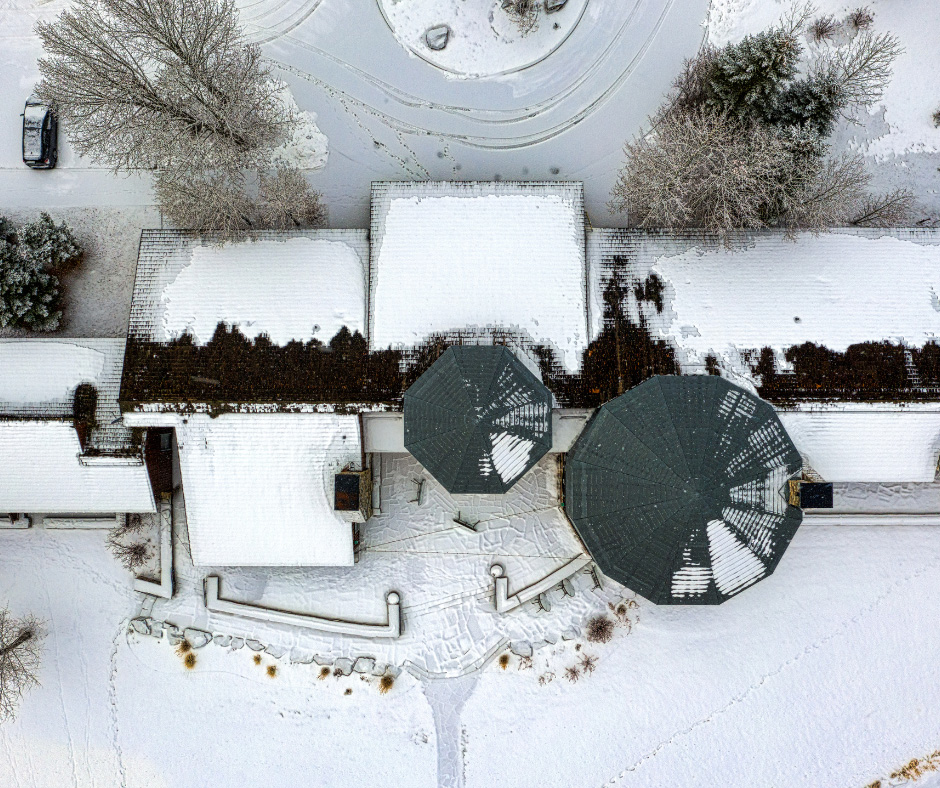 a building's roof viewed from directly overhead. The roof is partially covered in snow.