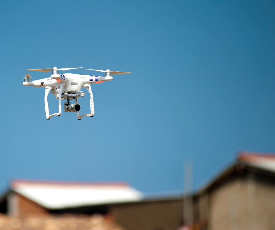 a camera drone hovers with a building's roof in the background