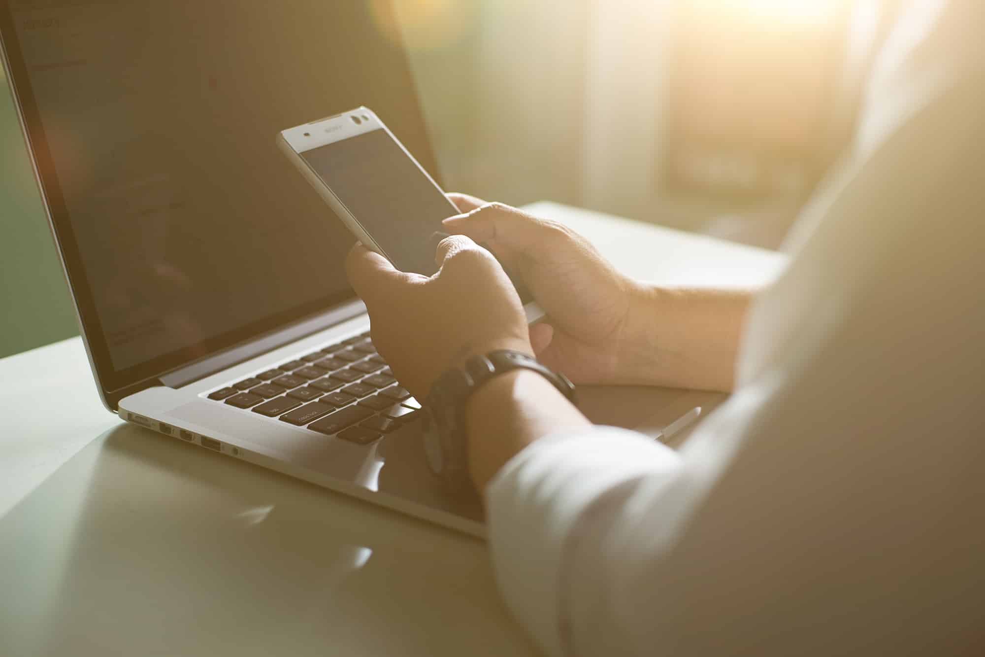 young man working from home using smartphone and notebook computer hands using smartphone
